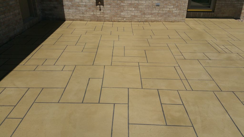 A large tan tile floor in front of a brick wall.