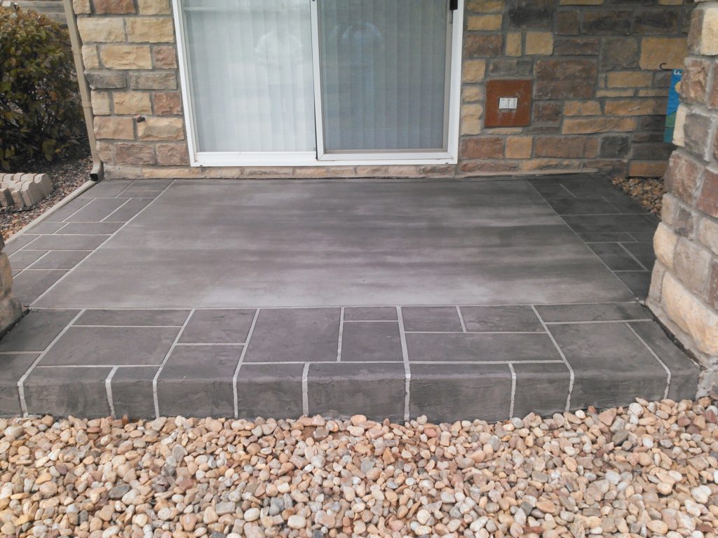 A patio with stone and gravel in front of the door.