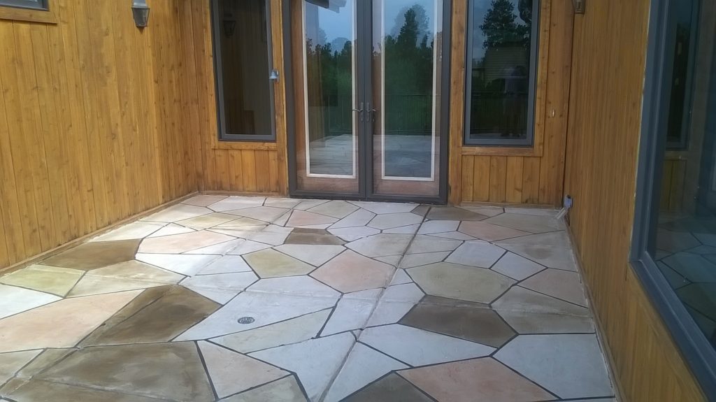 A patio with a large stone floor and two doors.